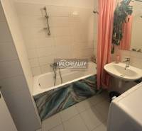 Koupelna s vanou, umyvadlem a pračkou ve 3-pokojovém bytě, dlažba s bílými obklady.