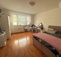 Ložnice v 3-pokojovém bytě s podlahou s dřevěným dekorem a velkým oknem.