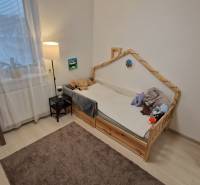 Dětský pokoj v 3-pokojovém bytě se světlou podlahou a poličkou plnou knih.