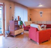 Obývací pokoj ve vile s červenou sedačkou a podlahou s dřevěným dekorem.