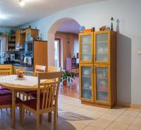 Kuchyně ve vile s dřevěným dekorem, jídelním stolem a vestavěnými skříňkami.