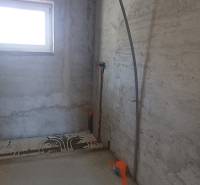 Interiér rodinného domu ve výstavbě s oknem a přípravou na instalaci rozvodů.