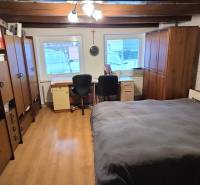 Pokoj v rodinném domě s podlahou s dřevěným dekorem, postelí a kancelářským koutem.