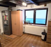 Kuchyně v rodinném domě s podlahou s dřevěným dekorem, stolem a lednicí.