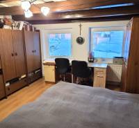 Pokoj v rodinném domě s dřevěným dekorem, pracovním stolem a úložnými skříňkami.