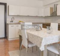 Kuchyně v rodinném domě s bílou linkou a jídelním stolem se čtyřmi židlemi.