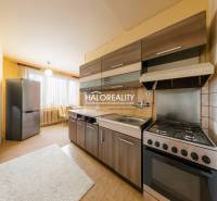 Kuchyně 3pokojového bytu s tmavými skříňkami, světlými stěnami a velkým oknem.