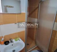 Koupelna s umyvadlem a sprchou v 1-pokojovém bytě, oranžovo-bílé obklady.