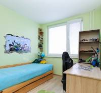 Dětský pokoj v 2-pokojovém bytě s postelí, psacím stolem a Minecraft dekorací na stěně.