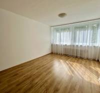 Světlá místnost se záclonami a podlahou s dřevěným dekorem ve 3-pokojovém bytě.