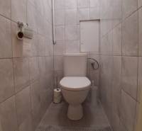 Koupelna ve 3-pokojovém bytě s keramickými obklady a toaletou.