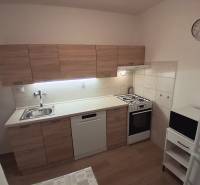 Kuchyně ve 3-pokojovém bytě s linkou, sporákem, myčkou a podlahou s dřevěným dekorem.