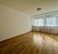 Světlá místnost s podlahou s dřevěným dekorem a velkým oknem v 3-pokojovém bytě.