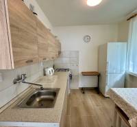 Kuchyně v 3-pokojovém bytě s podlahou s dřevěným dekorem a bílými stěnami.