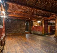 Interiér s podlahou s dřevěným dekorem, cihlové a kamenné stěny, strop s dřevěnými trámy.