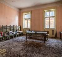 Ošuntělá místnost s lavicemi a nepořádkem ve staré budově.