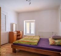 Ložnice s postelí, zrcadlem a podlahou s dřevěným dekorem.