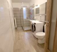 Koupelna v rodinném domě s kachlovým obkladem a podlahou s dřevěným dekorem.