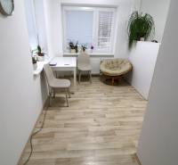 Pokoj v rodinném domě s podlahou s dřevěným dekorem, světlým nábytkem a rostlinami.