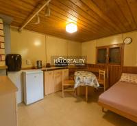 Pokoj s podlahou s dřevěným dekorem, jednoduchým zařízením, postelí a kuchyňským koutem.