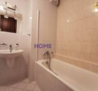 Koupelna v 2-pokojovém bytě s vanou, umyvadlem a zrcadlem.