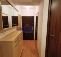 Předsíň v 2-pokojovém bytě s podlahou s dřevěným dekorem, zrcadly a skříněmi.