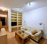 Obývací pokoj v 2-pokojovém bytě s krémovou sedačkou a podlahou s dřevěným dekorem.