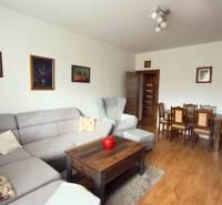 Obývací pokoj v 3-pokojovém bytě s rohovou sedačkou a podlahou s dřevěným dekorem.