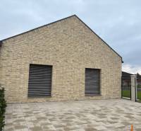 Rodinný dům na Fialkové ulici v Tomášově s cihlovou fasádou a dlážděným dvorem.