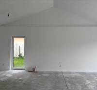 Bílá stěna a betonová podlaha v rodinném domě, připravené na dokončení interiéru.