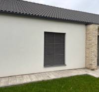 Exteriér rodinného domu na Fialkové v Tomášově s cihlovým obkladem a trávníkem.