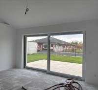 Rodinný dům se skleněnou stěnou a výhledem na zahradu.