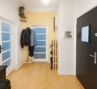 Chodba v 3-pokojovém bytě s podlahou s dřevěným dekorem, věšákem a dveřmi.