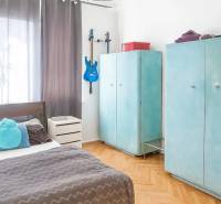 Interiér 3-pokojového bytu, dřevěný dekor podlahy, modrá kytara, útulná ložnice.