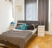 Ložnice s postelí, nočními stolky a podlahou s dřevěným dekorem ve 3pokojovém bytě.