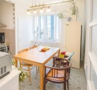 Jídelna ve 3-pokojovém bytě s dřevěným stolem, židlemi a dekorativní podlahou.