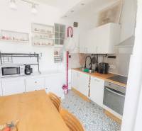 Kuchyně ve 3-pokojovém bytě s jídelním stolem, vzorovanou podlahou a bílými skříňkami.