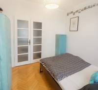 Ložnice v 3-pokojovém bytě s podlahou s dřevěným dekorem a světlými dveřmi.