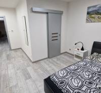 Ložnice v rodinném domě s podlahou s dřevěným dekorem a posuvnými dveřmi.