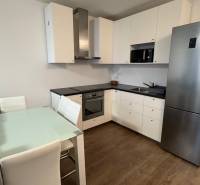 Kuchyňská linka v 1-pokojovém bytě s podlahou s dřevěným dekorem a jídelním stolem.