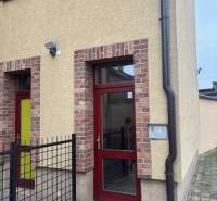 V Senci najdeš kanceláře v cihlové budově s červenými dveřmi.