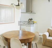 Jídelna s kulatým stolem v 3-pokojovém bytě, světlé stěny a podlaha s dřevěným dekorem.