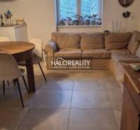 Obývací pokoj třípokojového bytu s pohovkou, jídelním stolem a dlaždicovou podlahou.