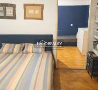 Ložnice v 3-pokojovém bytě s podlahou s dřevěným dekorem a barevným ložním prádlem.