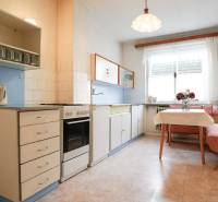 Kuchyně v rodinném domě s klasickým vybavením, rohovým sezením a oknem.