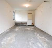 Garáž v rodinném domě s betonovou podlahou a bílými stěnami.