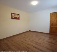 Pokoj s podlahou s dřevěným dekorem, obrazem na stěně a dřevěnými dveřmi.