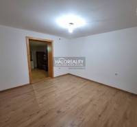 Interiér rodinného domu s podlahou s dřevěným dekorem a bílými stěnami.