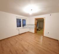 Pokoj v rodinném domě s podlahou s dřevěným dekorem a bílými stěnami.