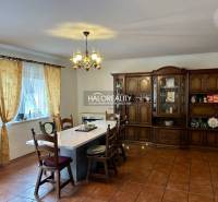 Prostorná jídelna v rodinném domě s velkým stolem a dřevěnou obývací stěnou.